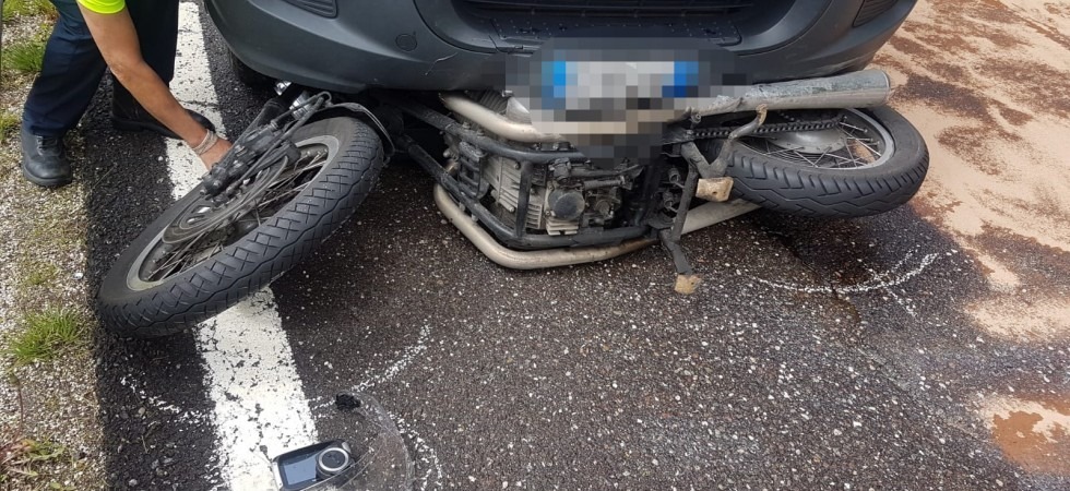 Slitta sul bagnato e finisce con la moto sotto il furgone